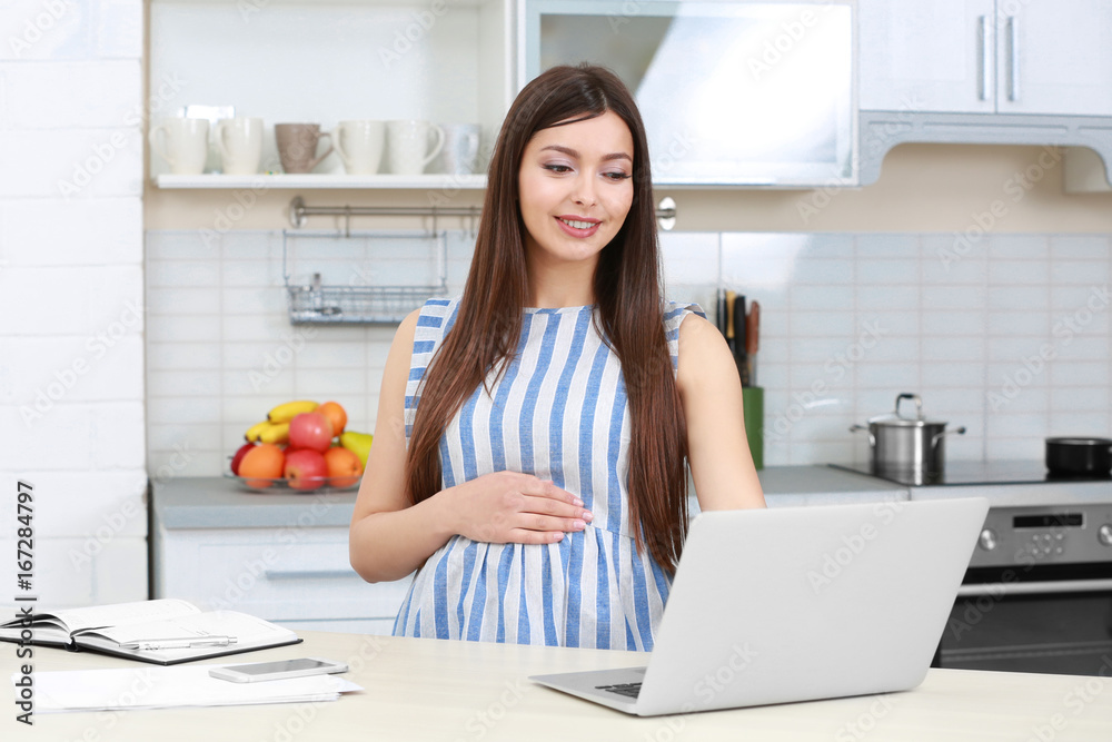 Beautiful young pregnant woman working in kitchen Beautiful young pregnant woman working in kitchen