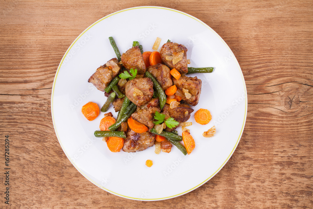 Sauteed liver with vegetables on white plate. View from above, top studio shot Sauteed liver with vegetables on white plate. View from above, top studio shot
