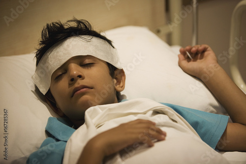 Boy sleeping with a damp cloth on his forehead 