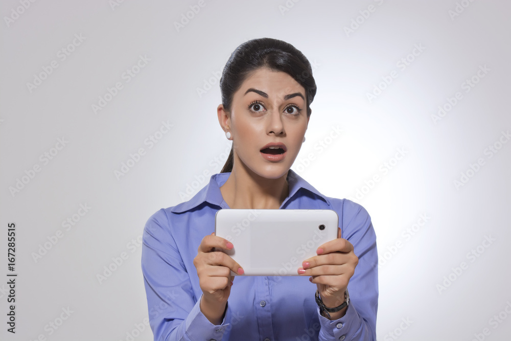 Amazed businesswoman holding digital tablet over gray background Amazed businesswoman holding digital tablet over gray background