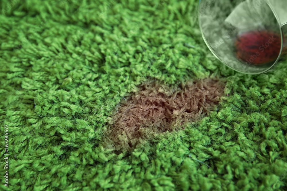 Glass of red wine spilled on green carpet, close up Glass of red wine spilled on green carpet, close up