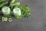 Mason jars with fresh smoothie and vegetables on grey background
