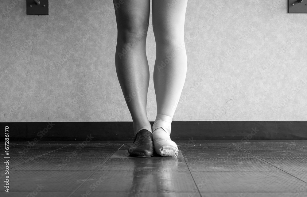 Black and white version of Dancer standing in parallel position at the barre, half dressed in Jazz dance attire and half in ballet attire Black and white version of Dancer standing in parallel position at the barre, half dressed in Jazz dance attire and half in ballet attire