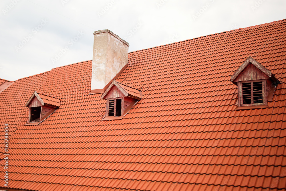 Orange roof with a chimney Old renewed orange roof with a white chimney and a roof window.