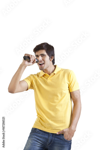 Portrait of young man with a microphone singing