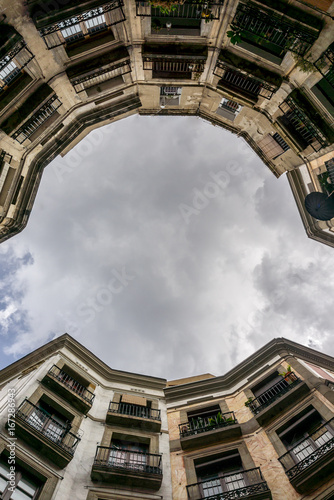 low angle shot of apartment building with balcony and cloudy sky. Barcelona, Spain
