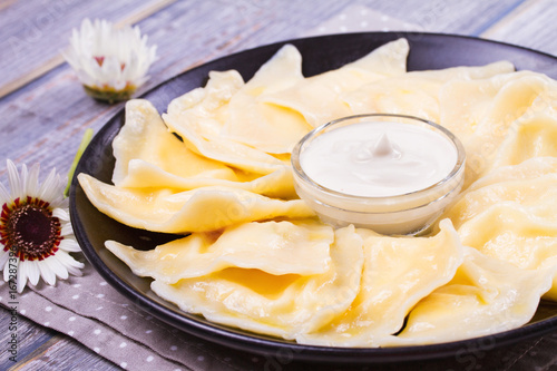 Varenyky, vareniki, pierogi, pyrohy or dumplings, filled with sweet cottage cheese (farmer cheese) and served with sour cream - traditional Ukrainian, Russian and Polish dish