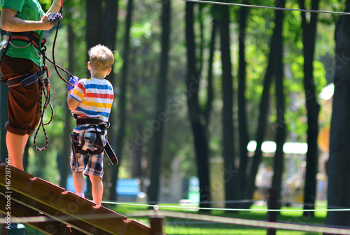 The coach coaches the child to climb in a rope park. photo