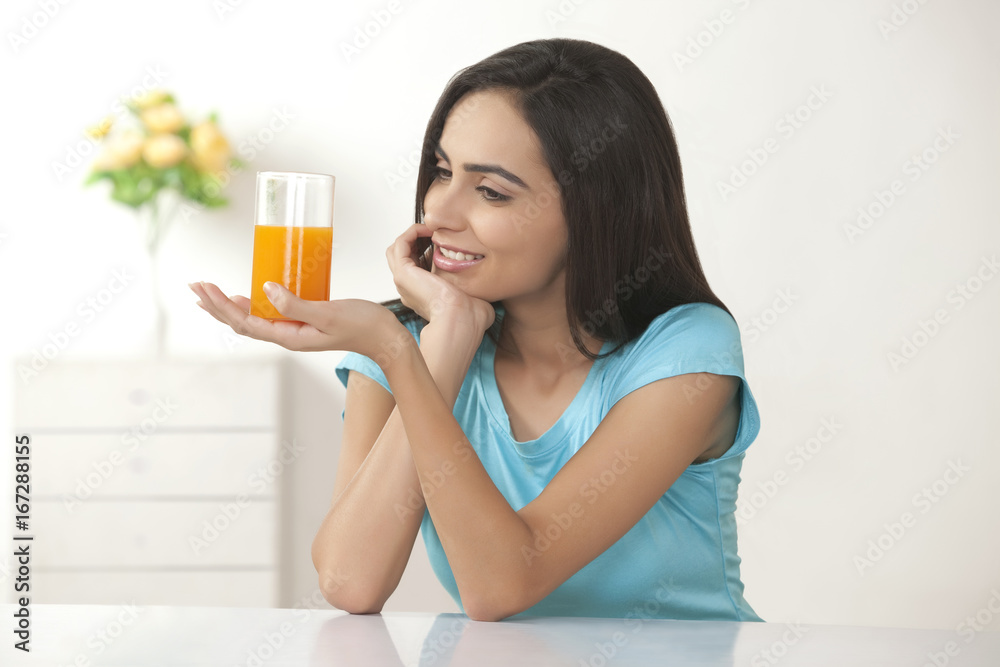 Beautiful young woman looking at glass of orange juice at home Beautiful young woman looking at glass of orange juice at home
