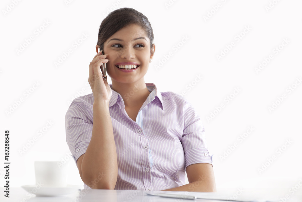 Smiling young businesswoman using cell phone at her desk Smiling young businesswoman using cell phone at her desk