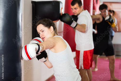 vigorous sportswoman in the boxing hall practicing boxing punches with boxing bag © JackF
