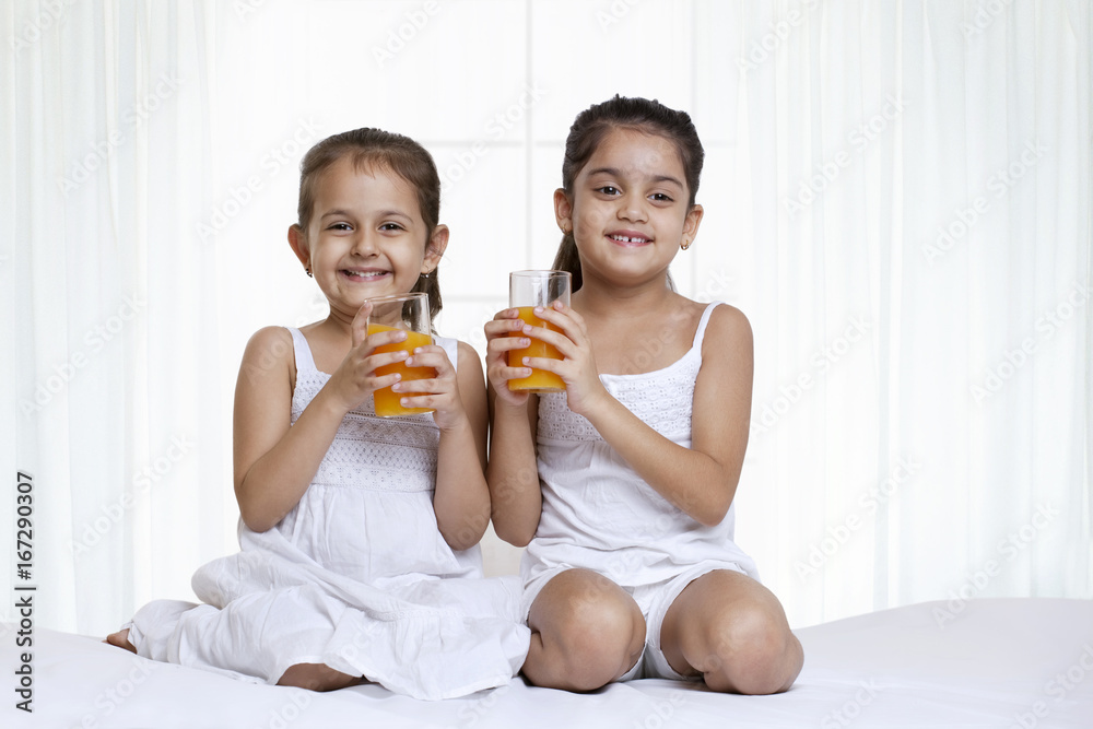 Portrait of sisters holding glass of juice Portrait of sisters holding glass of juice