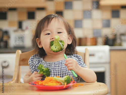 baby girl eating  vegetable at home