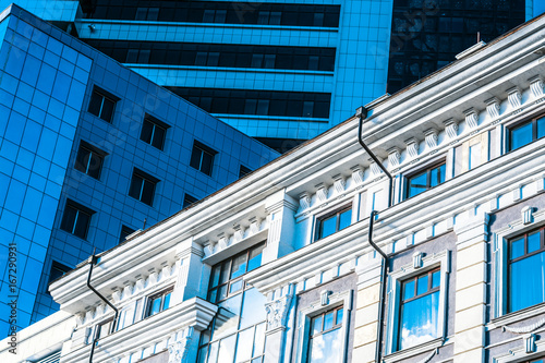 Fototapeta An ancient building next to a modern office building
