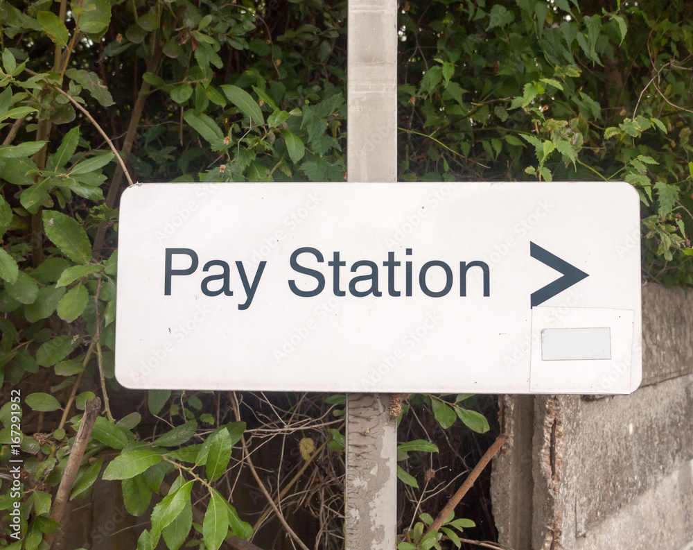 white pay station parking sign on metal post