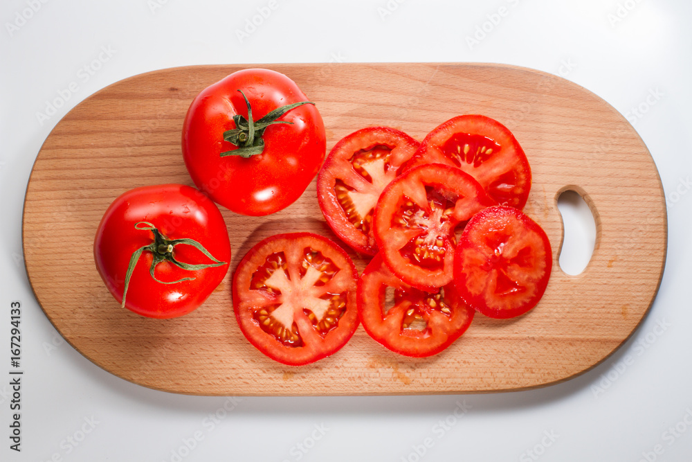 Sliced and whole tomatoes on a breadboard Sliced and whole tomatoes on a breadboard
