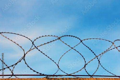 Barbed wire wall against of the blue sky closeup.