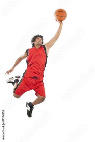 Basketball player in air preparing to dunk ball 