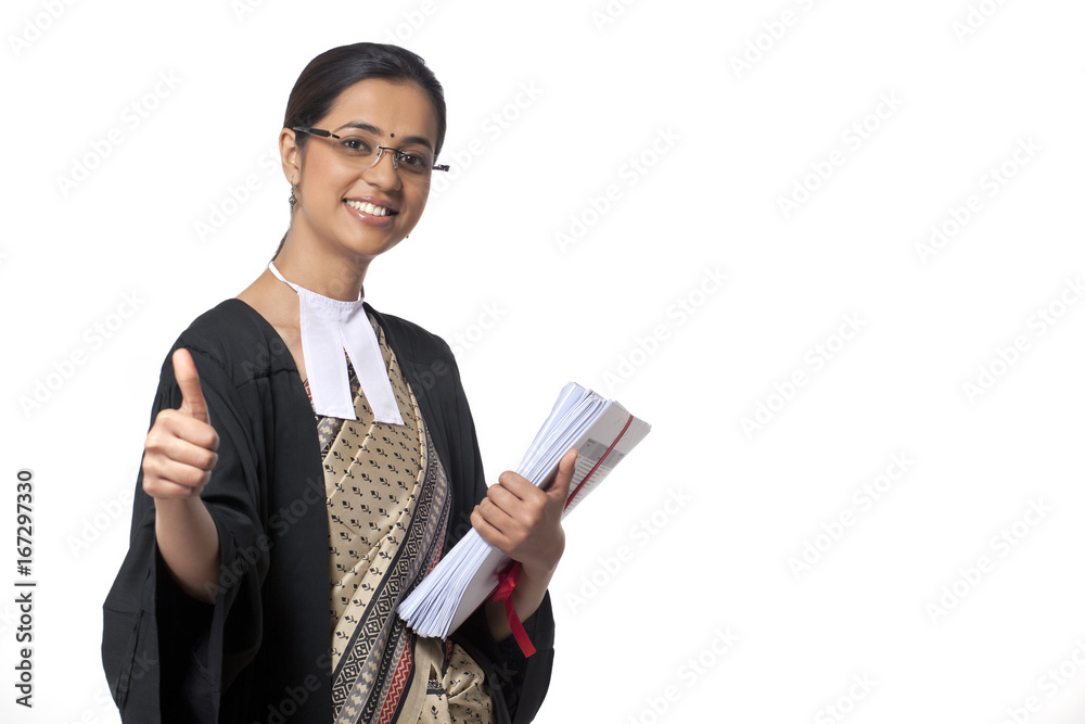 Portrait of young female lawyer showing thumbs up sign while holding documents against white background Portrait of young female lawyer showing thumbs up sign while holding documents against white background