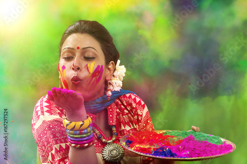 Photography Portrait of an Indian Woman celebrating Holi by blowing Holi powder