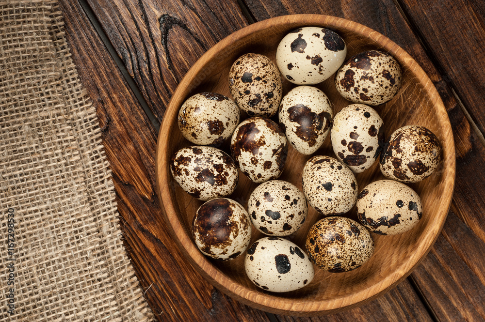 top view on quail eggs in wooden plate over old wooden background top view on quail eggs in wooden plate over old wooden background