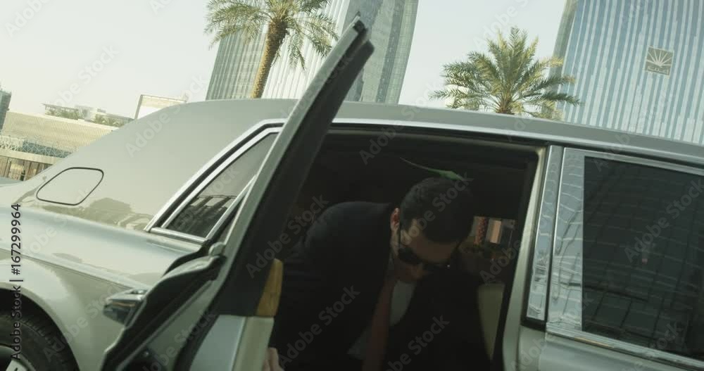Businessman gets out of fancy car, slow motion