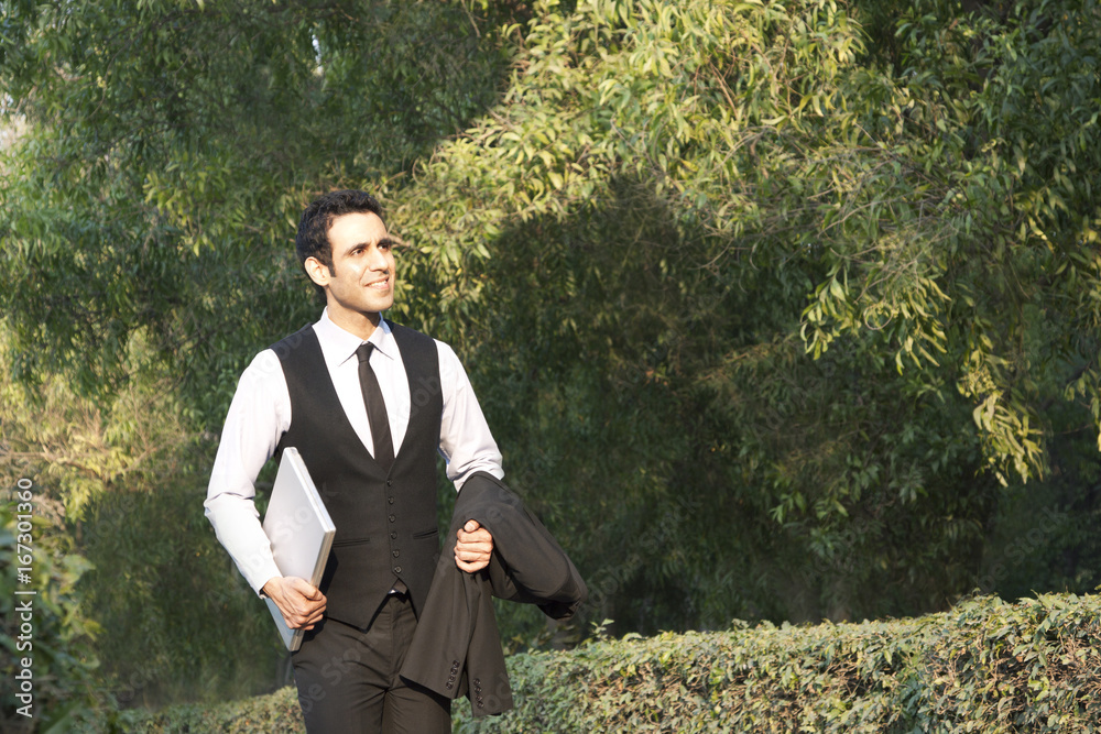 Businessman with laptop in a park , INDIA , DELHI Businessman with laptop in a park , INDIA , DELHI
