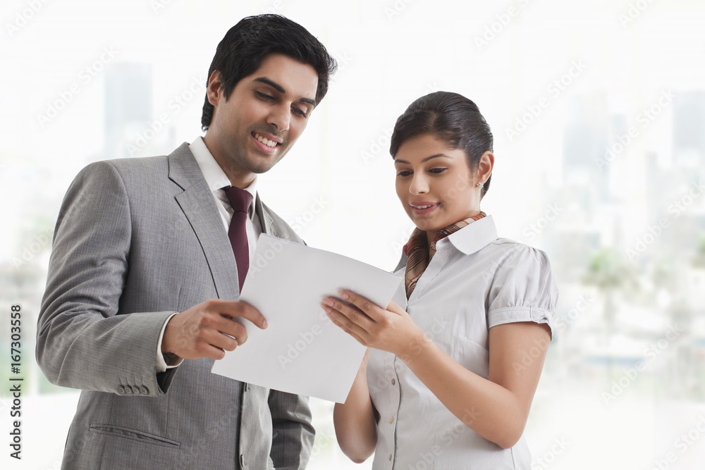 Young business colleagues looking at file in office Young business colleagues looking at file in office