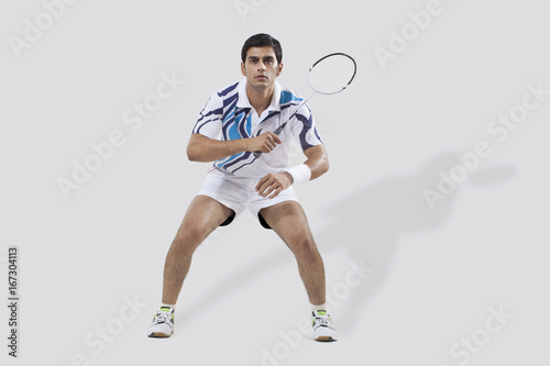 Full length of young man playing badminton isolated over white background