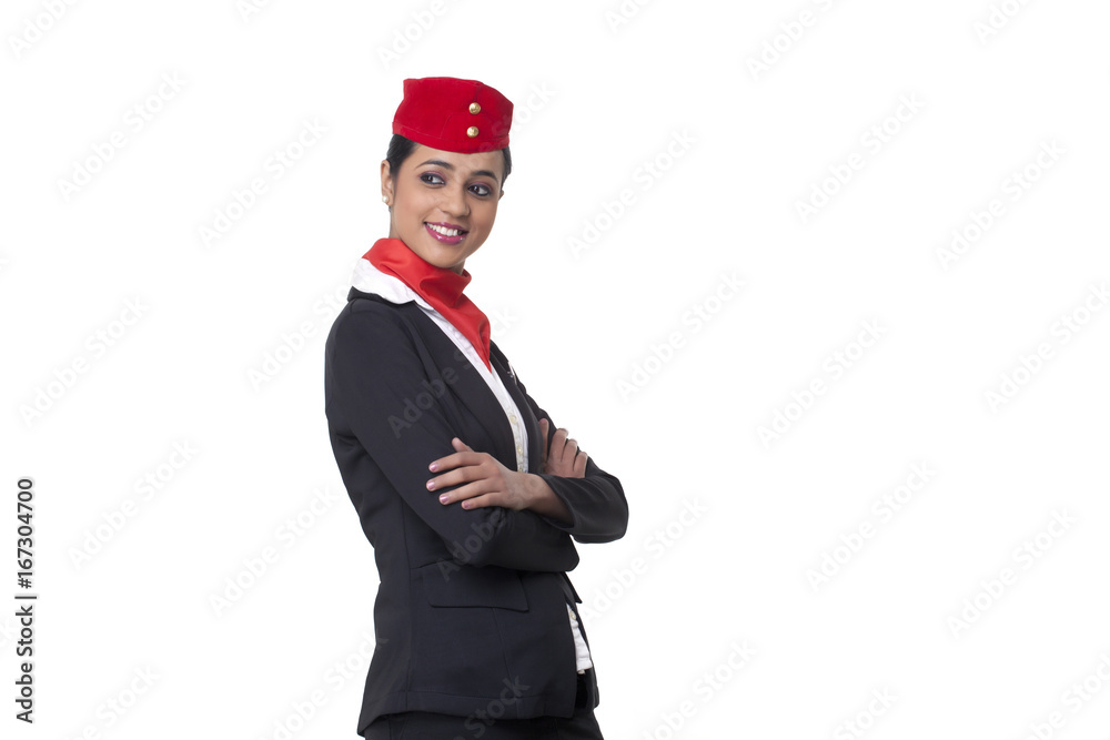 Young air hostess with arms crossed looking away against white background 