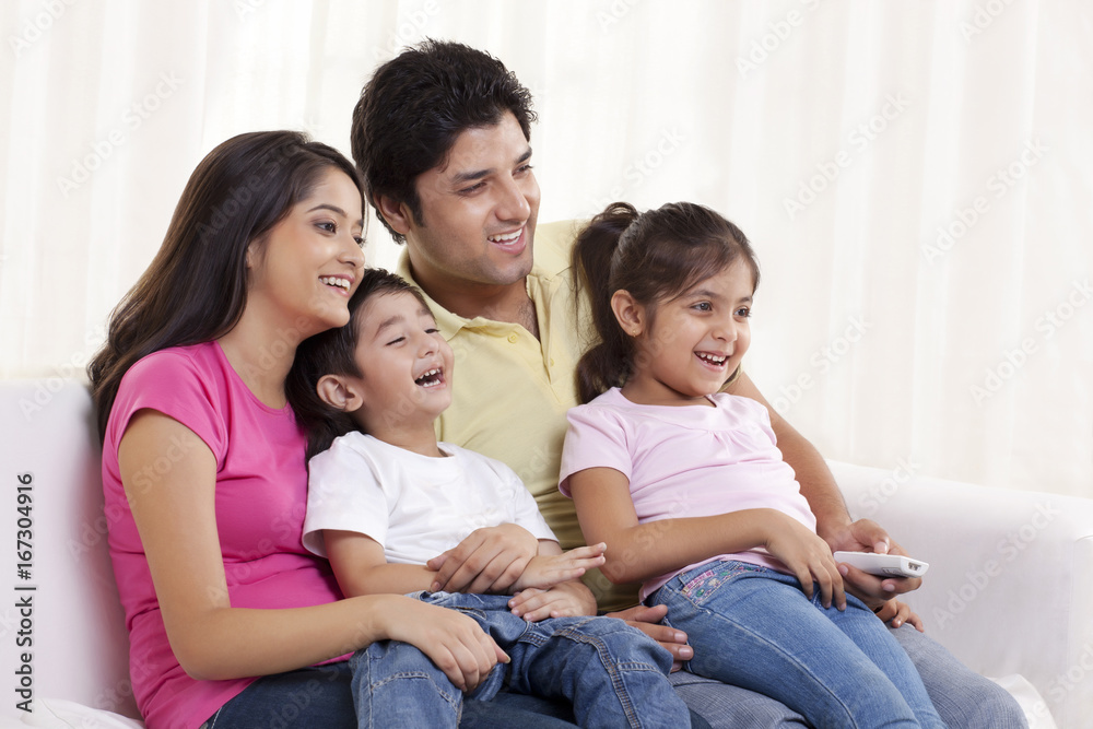 Family sitting on a sofa watching TV together Family sitting on a sofa watching TV together