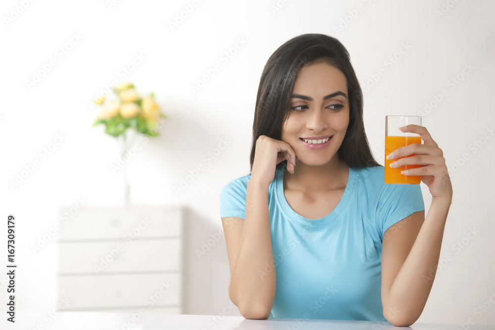 Beautiful young woman holding glass of fresh orange juice at home Beautiful young woman holding glass of fresh orange juice at home
