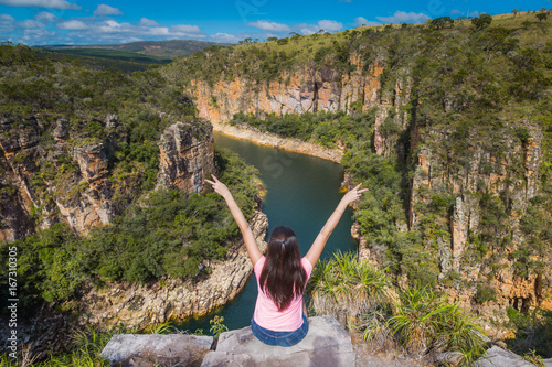 Freedom traveler woman with raised arms on the top of Furnas Canyon enjoying the beautiful landscape. Concept of travel and freedom. Capitolio, Minas Gerais, Brazil.
