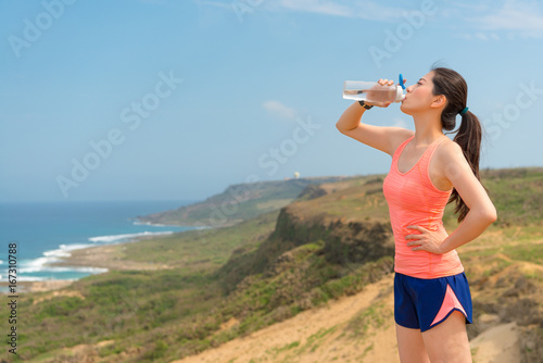 young athlete jogger on hill top holding bottle