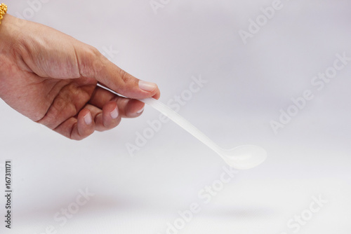 Hand Holding Measuring Spoon Over White Background