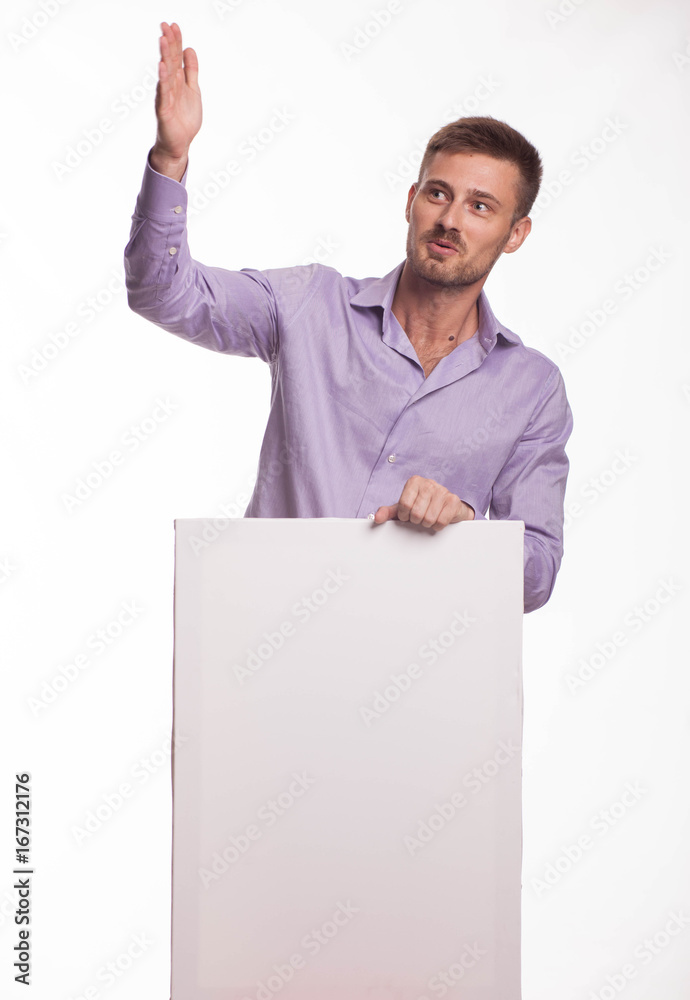 Young playful man portrait of a confident businessman showing presentation, pointing paper placard gray background. Ideal for banners, registration forms, presentation, landings, presenting concept. Young playful man portrait of a confident businessman showing presentation, pointing paper placard gray background. Ideal for banners, registration forms, presentation, landings, presenting concept.