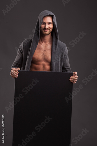 Young glad man portrait of a confident businessman showing presentation, pointing paper placard black background. Ideal for banners, registration forms, presentation, landings, presenting concept.