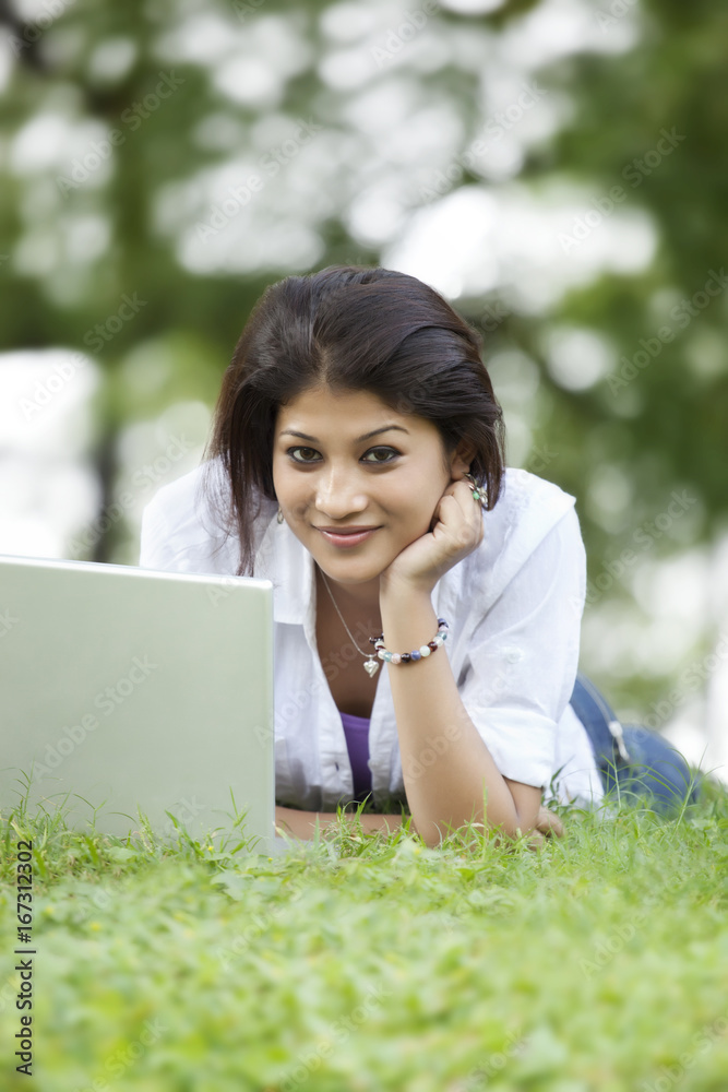 Portrait of woman lying on grass in lawn and using laptop Portrait of woman lying on grass in lawn and using laptop