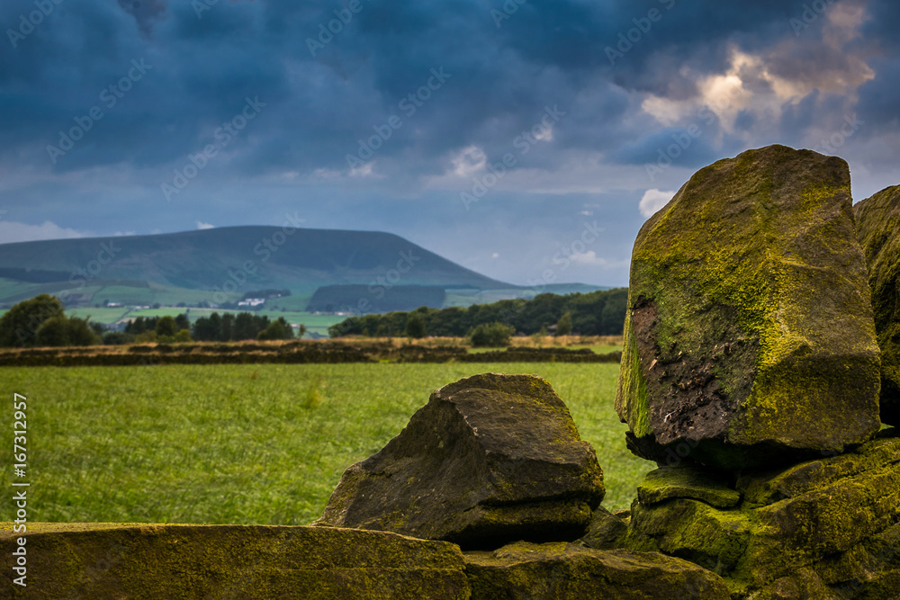 Stone wall stones on the farm with distance clouds formation over Forest of Bowland on summer afternoon