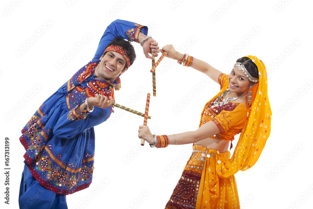 Φωτογραφία Portrait of happy young couple in traditional wear performing Dandiya Raas again