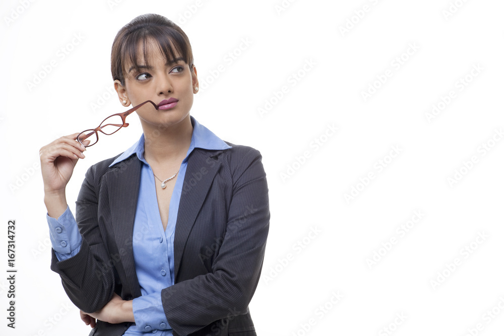 Beautiful young female executive holding glasses while looking away Beautiful young female executive holding glasses while looking away