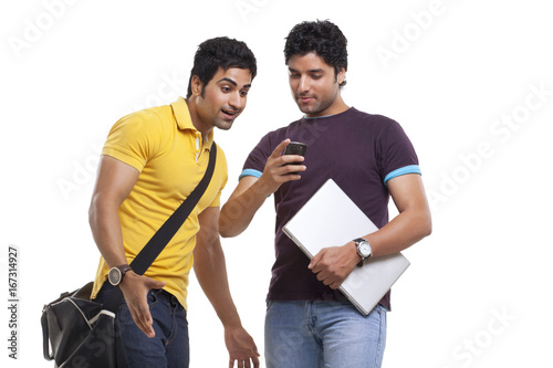 Surprised man looking at friend's cell phone 