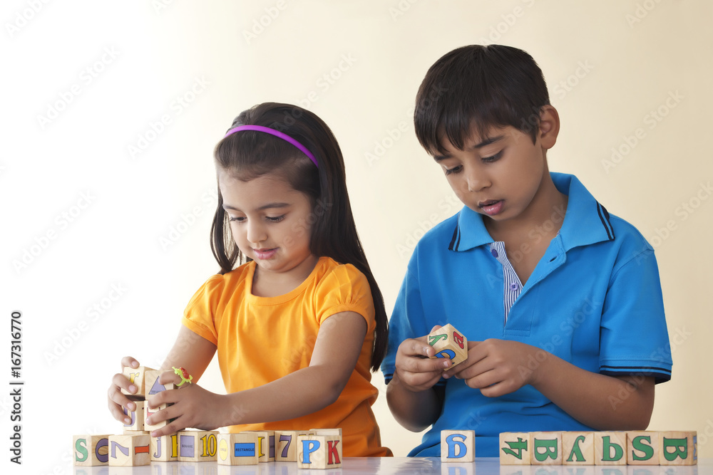 Siblings playing with blocks against colored background Siblings playing with blocks against colored background