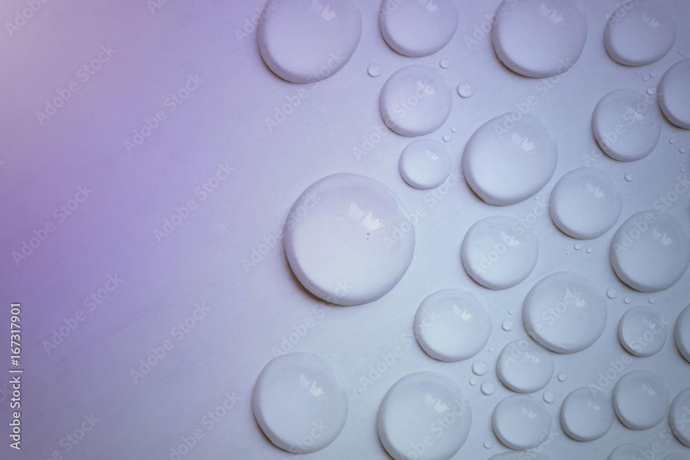 Big and small water drops on purple background. Closeup.