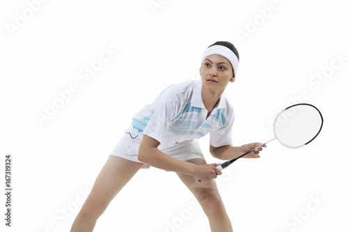 Young woman holding badminton racket while looking away isolated over white background © IndiaPix