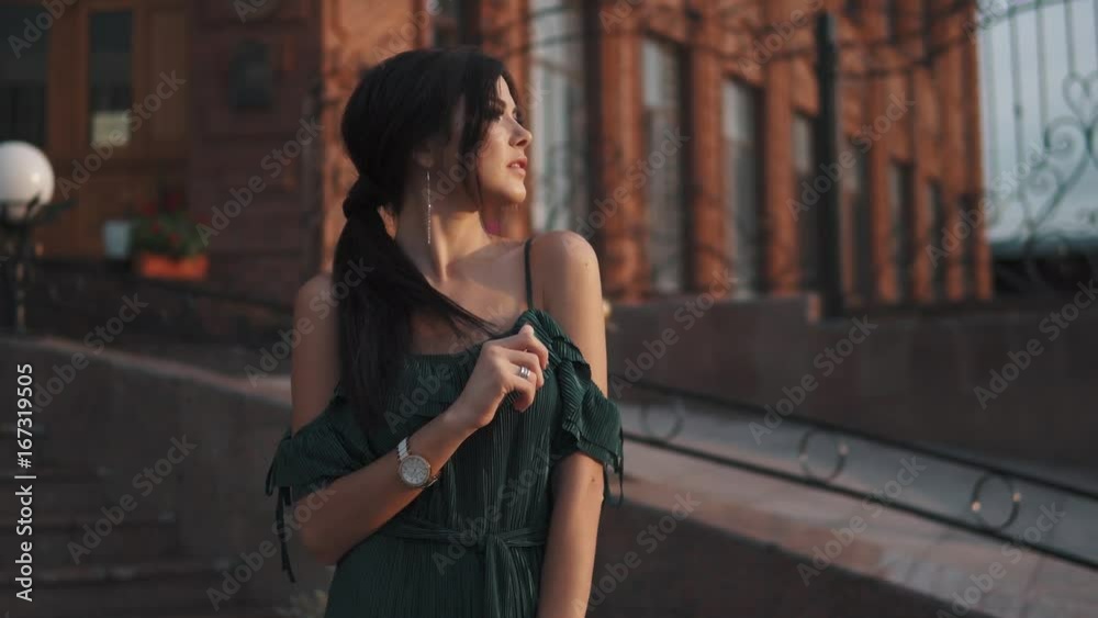 portrait of beautiful girl with evening makeup and hairstyle. cute brunette posing for the camera at sunset on the background of the city portrait of beautiful girl with evening makeup and hairstyle. cute brunette posing for the camera at sunset on the background of the city