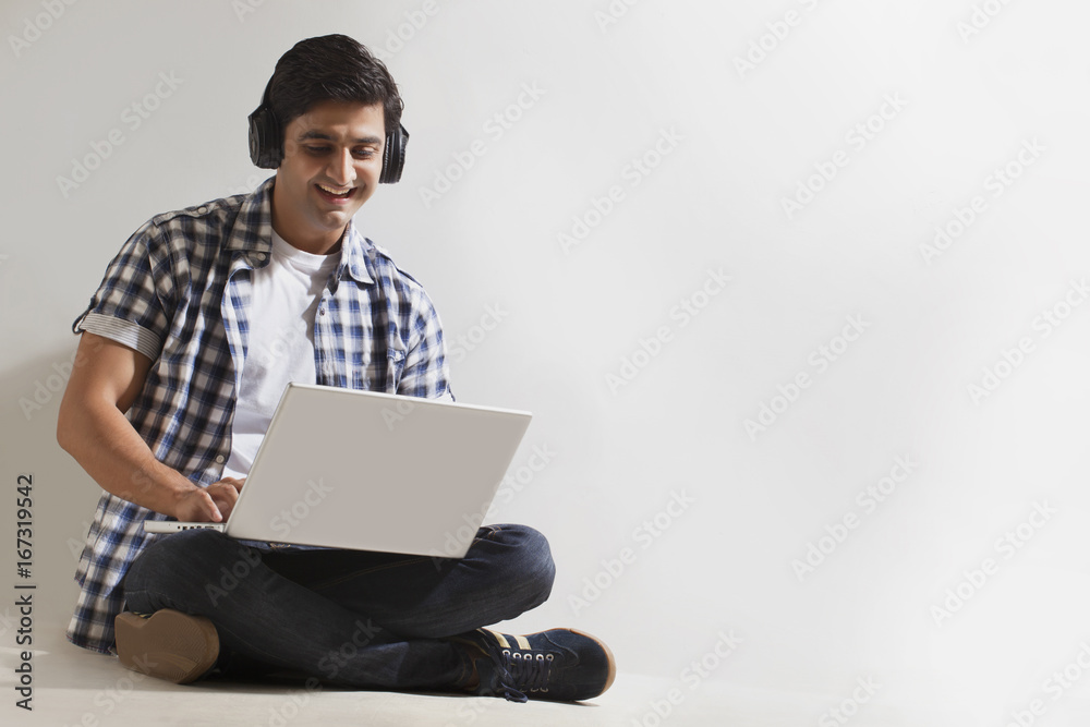 Man wearing headphones and using laptop Man wearing headphones and using laptop
