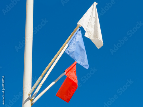 Flags of different colors on the background of blue sky.