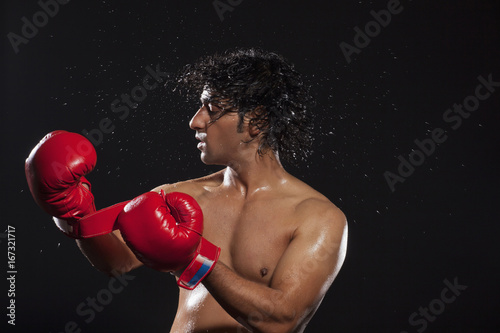 Young man tossing hair while wearing boxing gloves  © IndiaPix
