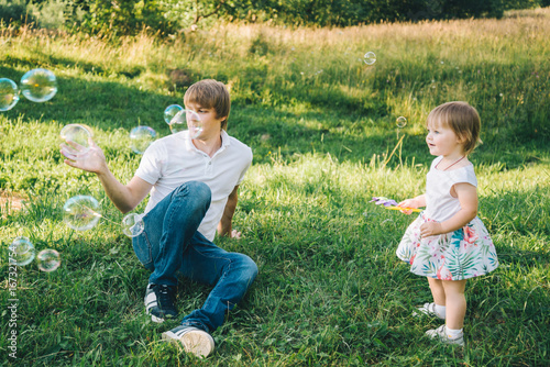 father plays with his daughter with soapbubble photo